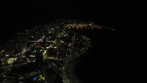 luminous urban landscape of punta del este uruguay spreading along coastal shoreline, revealing sparkling metropolitan scenery beneath darkening sky with expansive nighttime panorama