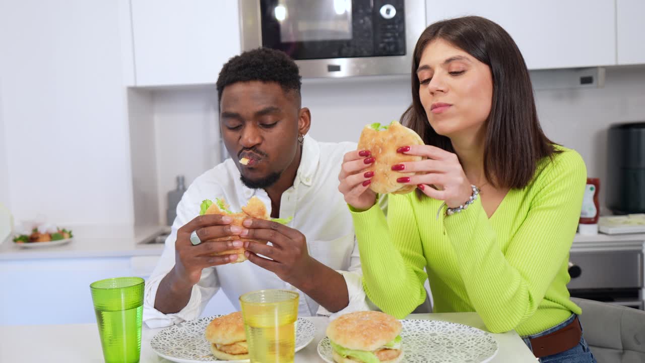 People Enjoying Burgers at a Kitchen Table