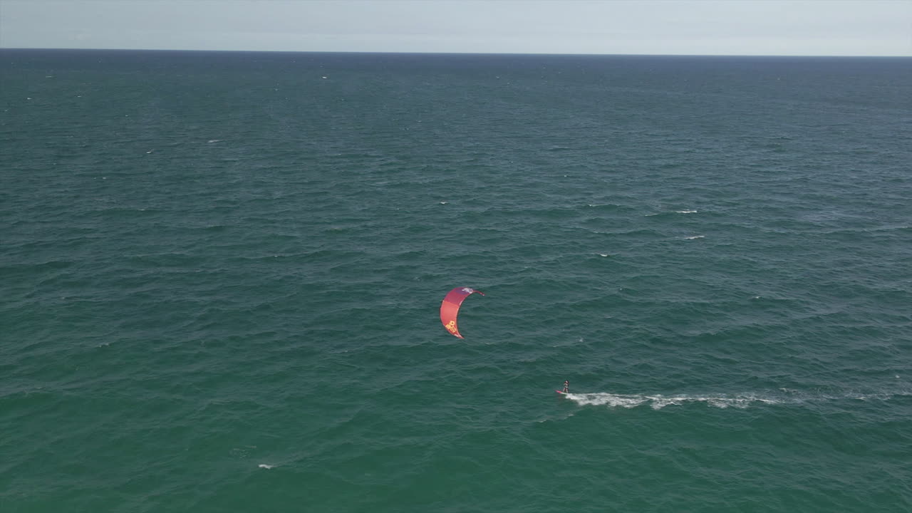 antena: kite surfista acelera a favor del viento rápidamente en la extensión vacía del océano
