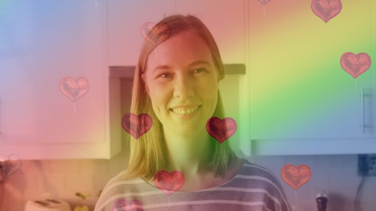 Animation of heart emojis and rainbow flag over caucasian woman smiling