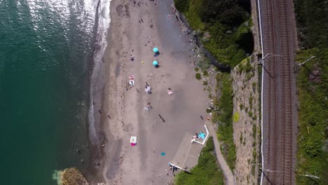 Toma-Aérea-De-Arriba-Hacia-Abajo-De-Una-Playa-Junto-Al-Ferrocarril-En-Dalkey,-Irlanda