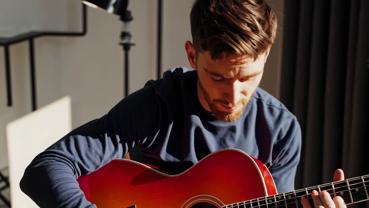 hombre tocando la guitarra acústica en una sala de estar moderna con vistas a la ciudad