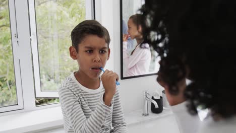 Happy-biracial-brother-and-sister-with-couple-brushing-teeth-in-sunny-bathroom,-slow-motion