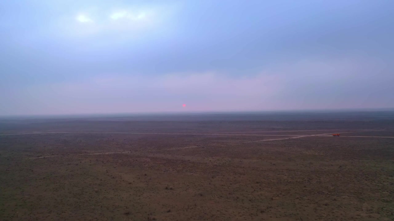 Wide aerial view of gas field landscape under soft sunset sky.