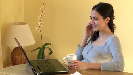 mujer seria en el teléfono trabajando en una computadora