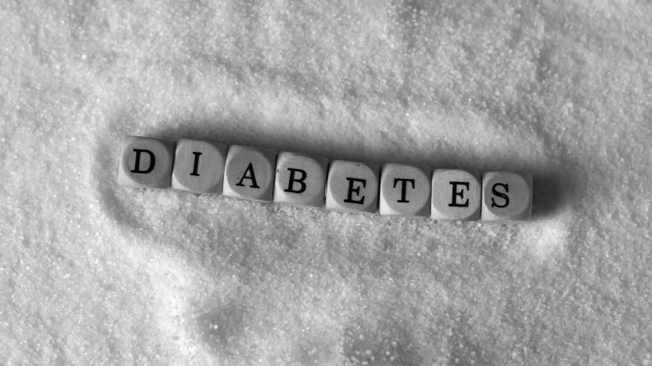 Dados formando la palabra diabetes cayendo en un montón de azúcar