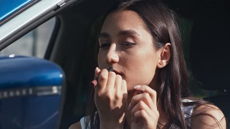 mujer aplicando lápiz labial en el coche