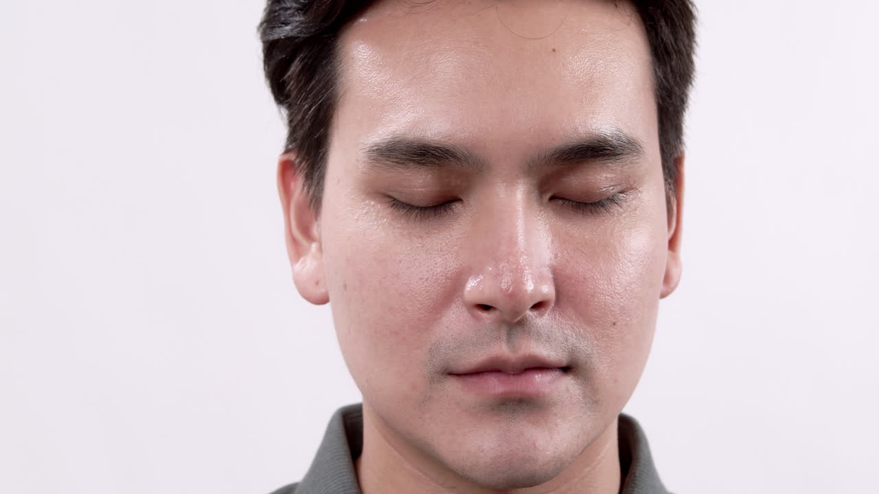 A cheerful young man smiles warmly capturing a moment of joy in a simple studio setting.