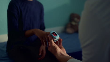 physician checking blood saturation teen girl using oximeter in clinic close up.