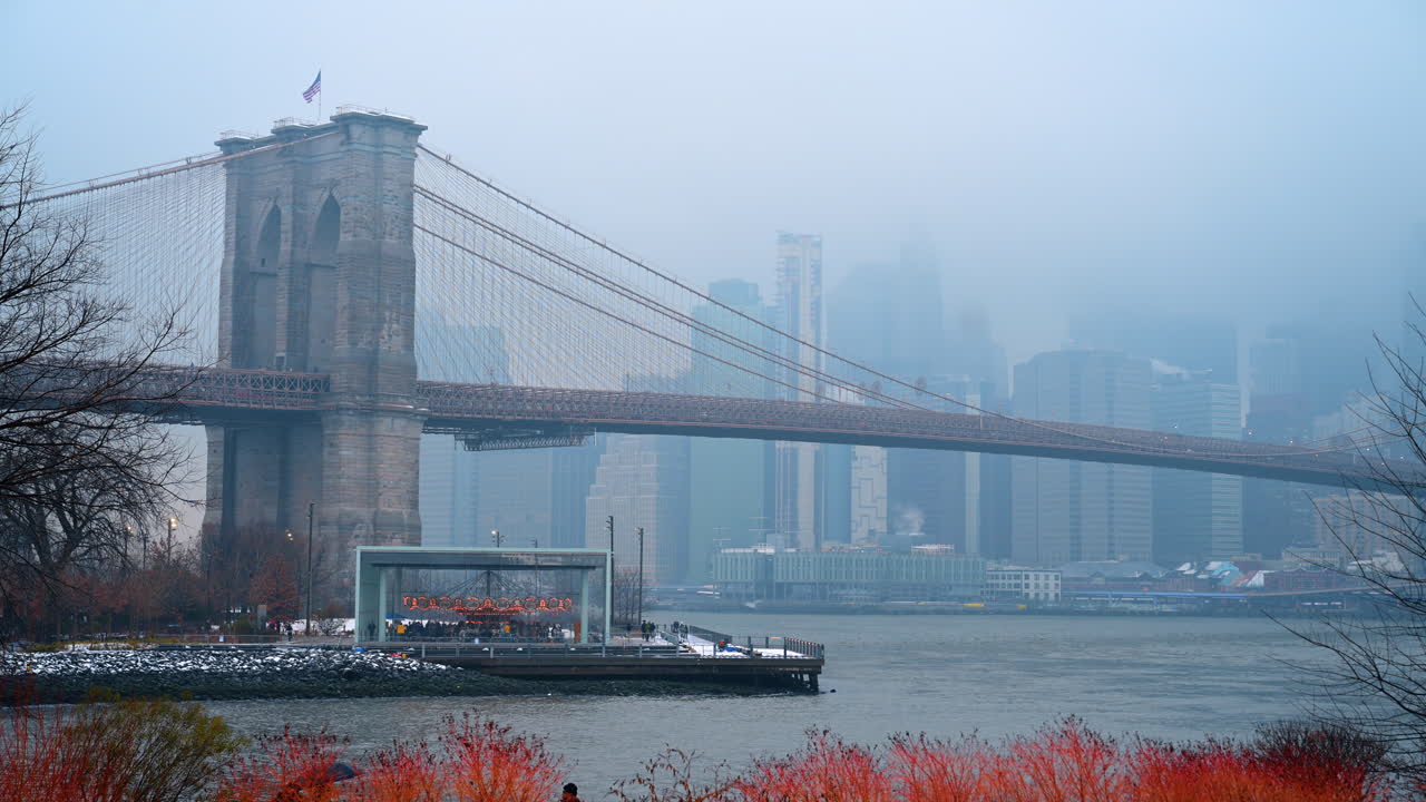 Brooklyn Bridge and Manhattan skyline in foggy winter weather. Long shot of the Brooklyn Bridge over the East River during a hazy, misty day