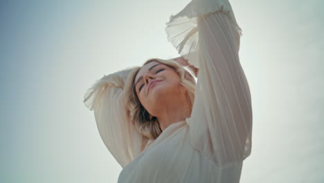 gorgeous woman posing sunlight raising hands to sky close up. girl enjoy summer.