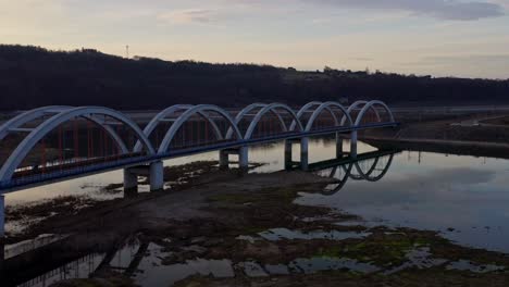 puente de arco ferroviario que cruza el río skawa con aguas poco profundas y tranquilas durante la puesta de sol