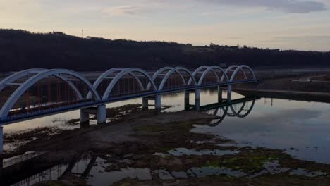 railroad arch bridge spanning the skawa river with shallow and calm waters during sunset