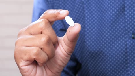 hand holding a white pill