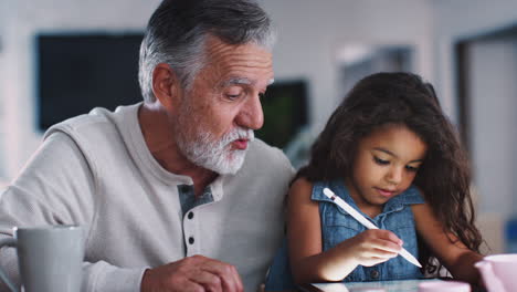 Älterer-Mann-Spricht-Mit-Enkelin,-Während-Sie-Einen-Stift-Und-Einen-Tablet-Computer-Verwendet,-Nahaufnahme,-Handheld