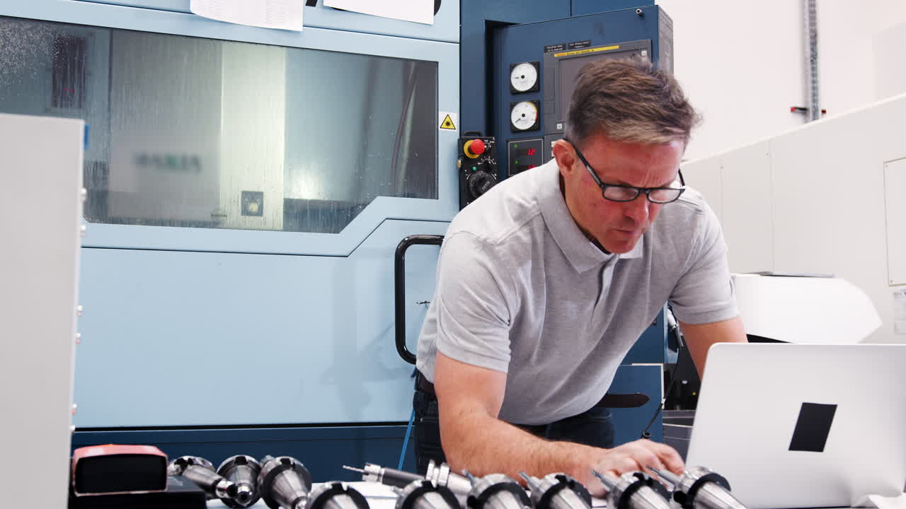 Male Engineer Using Laptop And Measuring Components In Factory