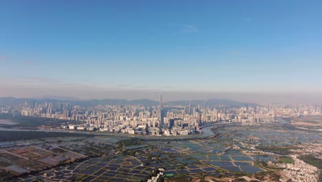 Hong-Kong-and-Shenzhen-border-line-over-Hong-Kong-rural-houses-with-Shenhzen-skyline-in-the-horizon,-Aerial-view