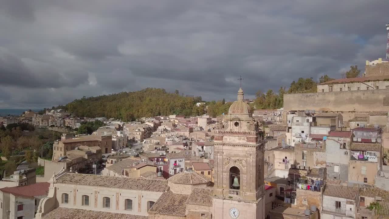 Aerial footage of medieval city of Caltagirone. Drone flies by historic church tower, revealing the old citadel overlooking the castle. Beautiful city landscape shot.