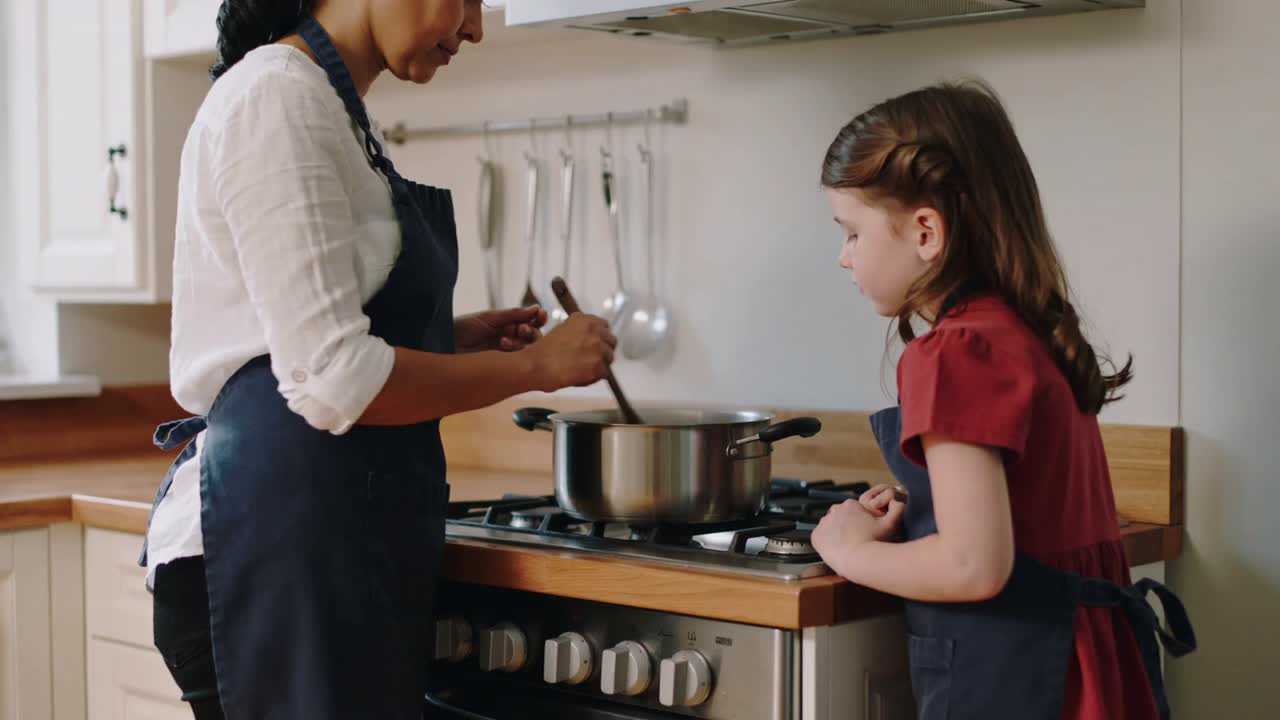 Mujer adulta revolviendo, enseñando a un niño para la cena en la estufa de la cocina de casa, con olla, cuchara, delantales.