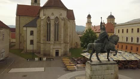 Aerial-Upwards-Pan-of-Statue-of-Mihai-Viteazul-in-Alba-Iulia-with-the-back-of-the-church-and-trees