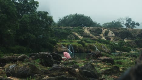 man sitting and cleansing in nature with small waterfalls and river