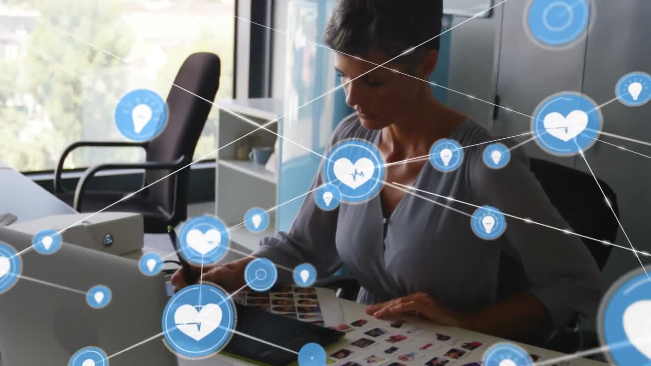 animación de una red de iconos digitales sobre una diseñadora gráfica caucásica que utiliza una tableta gráfica