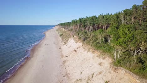 vista aérea de la playa del mar báltico en jurkalne en un día soleado, acantilado de arena blanca dañado por las olas, erosión costera, cambios climáticos, tiro de drones de gran angular moviéndose hacia atrás