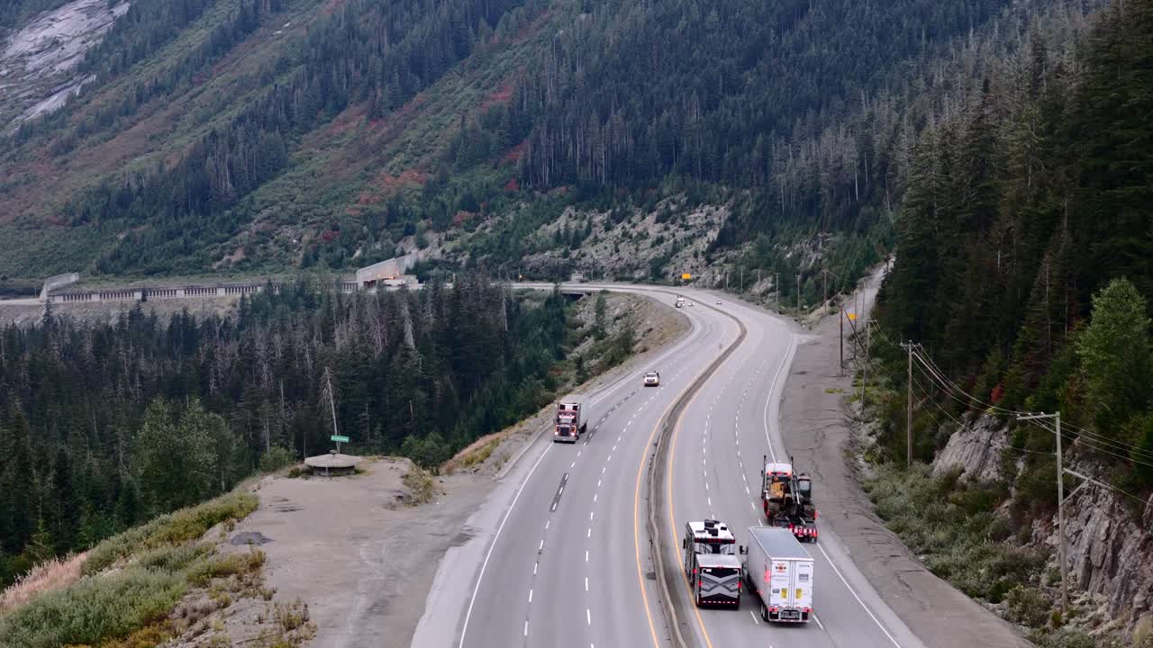 Autocarro che trasporta un escavatore lungo le ripide pendenze dell'autostrada Coquihalla