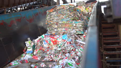 toma cinematográfica de balas de cartones de leche y jugo aplanados en un transportador en un umbral de planta de reciclaje en balas de material reciclado