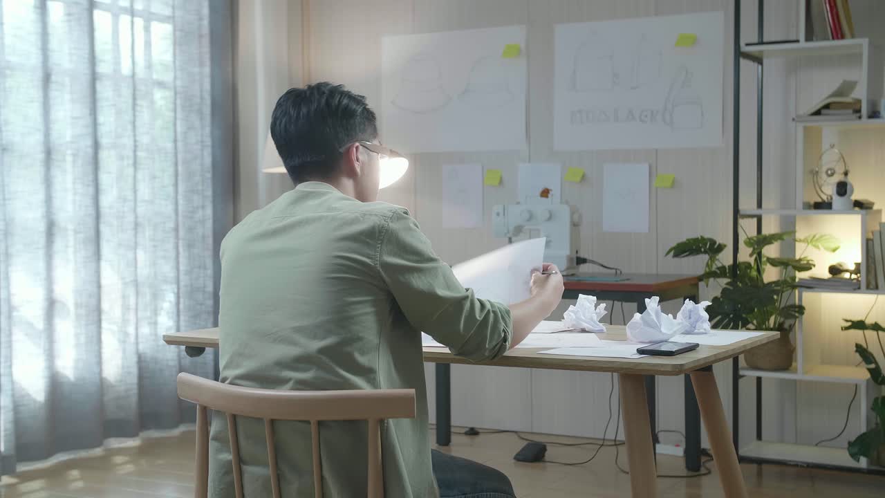 아시안 남자 디자이너의 뒷면은 레이아웃을 그리는 데 실패하여 화가 나고 그것을 버립니다.