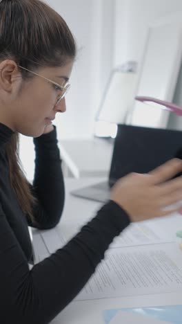 woman studying and working at a desk with laptop and papers