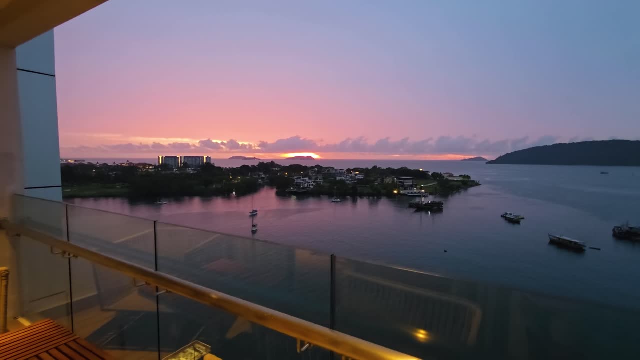 Aerial-style view from Marriott Hotel balcony in Kota Kinabalu, Malaysia, capturing a vivid sunset over calm sea with boats near Sutera Harbor in a peaceful tropical coastal setting