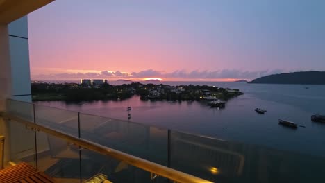 aerial-style view from marriott hotel balcony in kota kinabalu, malaysia, capturing a vivid sunset over calm sea with boats near sutera harbor in a peaceful tropical coastal setting