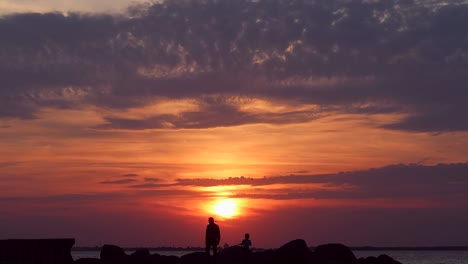 a father and his son walking down the coast at sunset