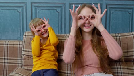 Mother-and-little-child-kid-daughter-having-fun-sitting-on-sofa-fooling-around,-making-faces-at-home