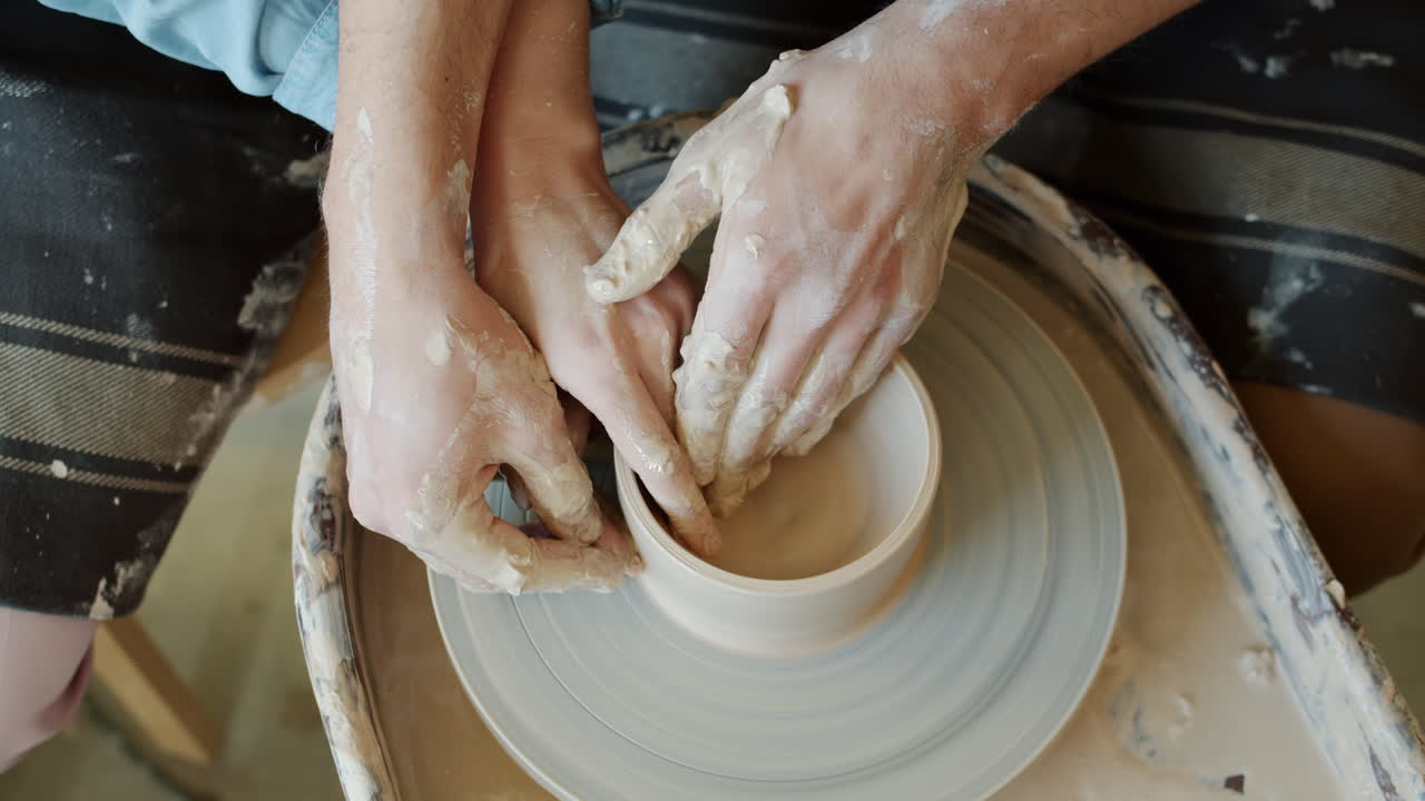 manos moldeando arcilla en una rueda de cerámica