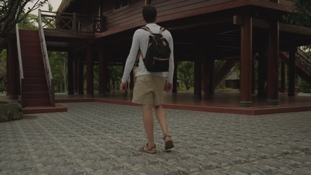 Tourist Walks Through a Wooden House in a Tropical Village