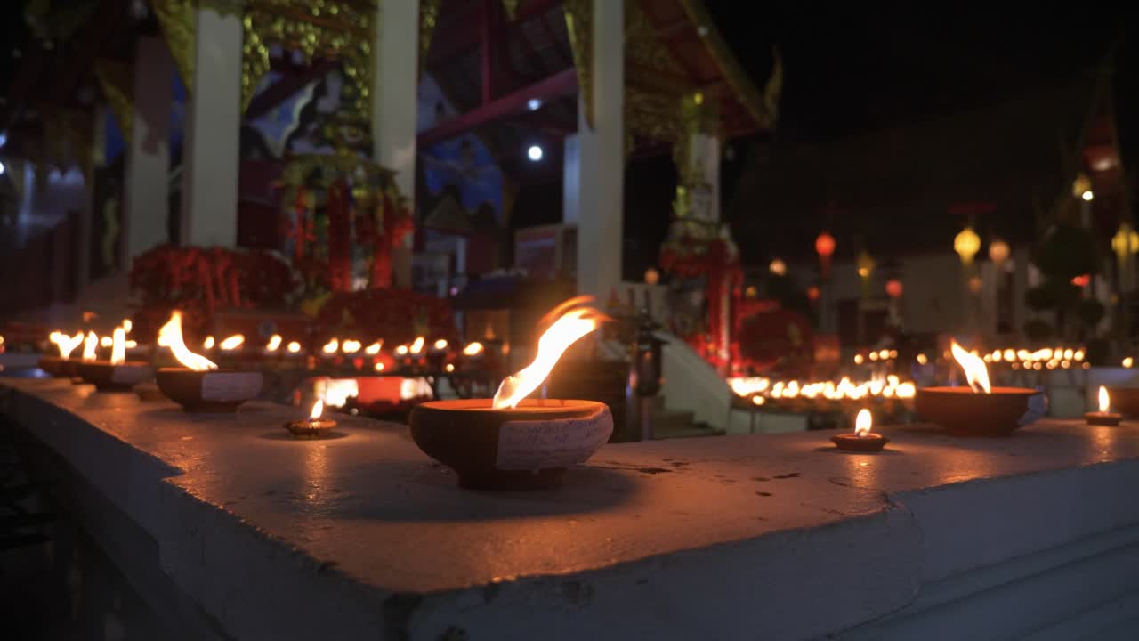 innumerables velas sagradas y tradicionales ardiendo frente al templo budista en la noche durante el festival loy krathong en chiang mai, tailandia