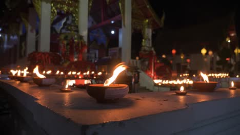 Countless-traditional-and-holy-candles-burning-infront-of-buddhist-temple-at-night-time-during-Loy-Krathong-Festival-in-Chiang-Mai,-Thailand