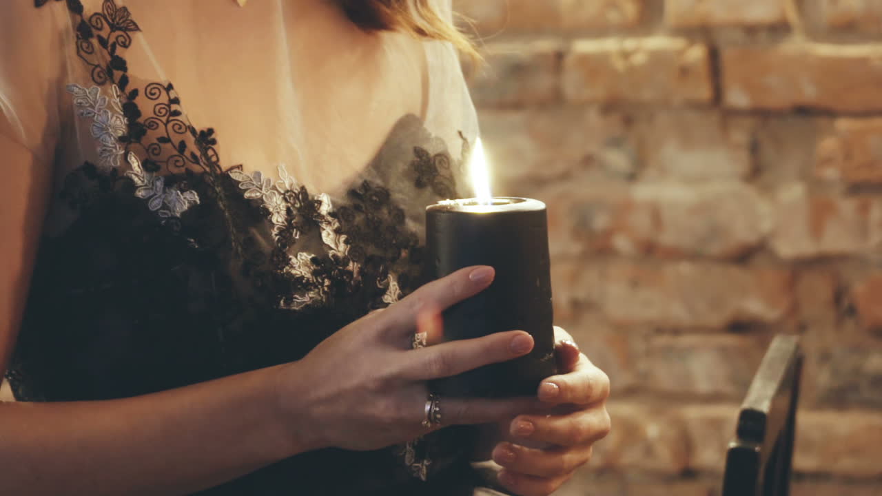 Dark story about witch. Woman in a witches costume guessing with candle