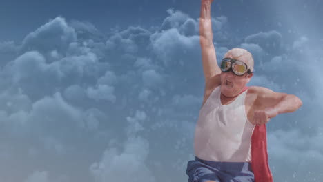 animation of clouds over happy senior caucasian man wearing superhero costume on beach