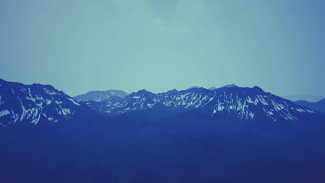 mountains with snow capped peaks under a blue sky in the early morning