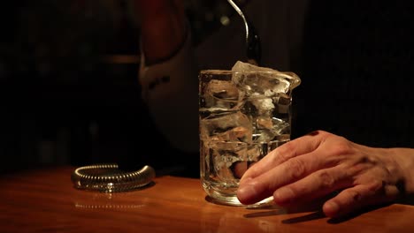 bartender adding ice to a glass at a bar