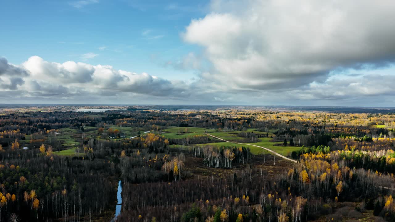 Aerial drone hyperlapse over verdant countryside landscape in autumn covering vast area of land and forest. Small village from above in rural area.