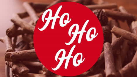 animation of ho ho ho text in red circle over cinnamons and pinecones