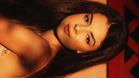 vertical close up medium shot of a young attractive woman with brown hair looking elegantly at the camera while closing her eyes during the golden hour to the sunset in slow motion