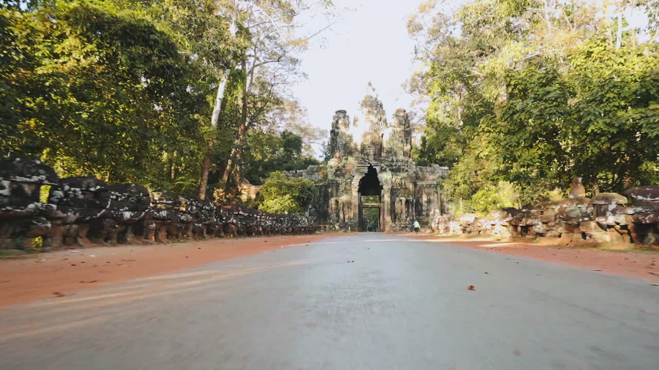 First person view riding a motorcycle leaving through Victory Gate, Angkor Wat Thom Cambodia