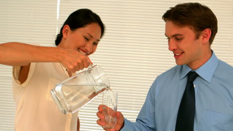 Geschäftsfrau-Gießt-Ihrem-Partner-Ein-Glas-Wasser-Ein