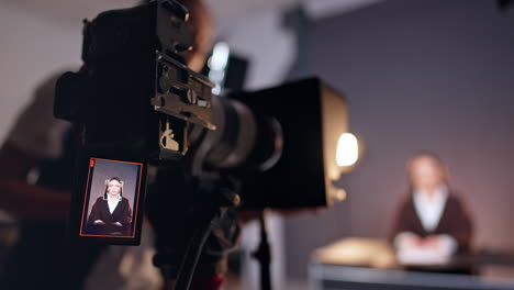 brunette caucasian lady on the display of modern camera. close up. unrecognized woman stands near the camera fixing equipment. blurred backdrop