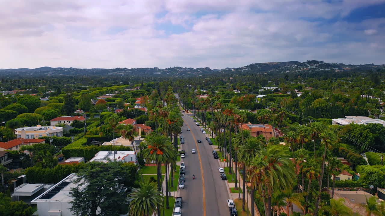 Los Angeles, USA, 29 August 2025: Flight over the road across the beautiful residential area in lush greenery. Brilliant scenery of LA, California, USA on a gloomy day